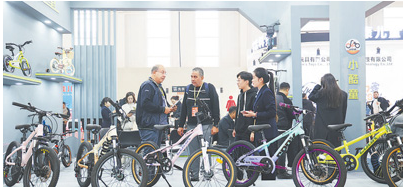 1765861272545219.png 在中国·北方(平乡)国际自行车童车玩具博览会上,参展企业工作人员向外.png